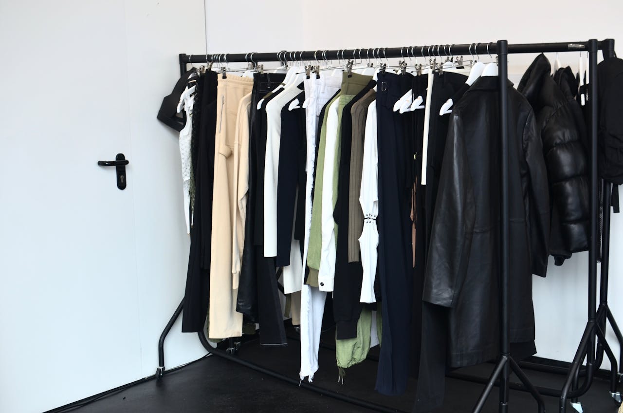 Stylish wardrobe with diverse clothing collection on a black rack in a bright room.
